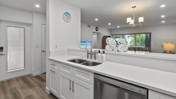 A modern kitchen with white cabinetry, a stainless steel dishwasher, and a double sink.
