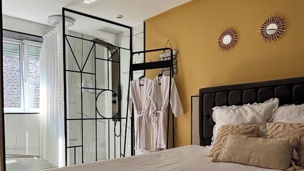 A bedroom with a bed, a black headboard, and two wall-mounted decorative items. - Ô Saphir Spa - House N2 (Denain)