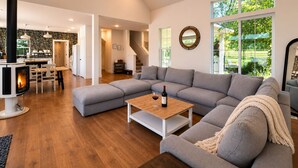 Een moderne woonkamer met een modulaire bank, een salontafel, een open haard en grote ramen.