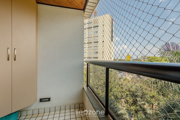 A balcony with a view of a tall building and surrounding greenery. - Apart in a Condo With a Pool in Asa Sul Bhe0405 (Brasília)