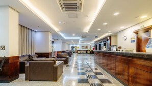 Un hall d’hôtel avec des canapés en cuir, un comptoir de réception et un guichet d’enregistrement.