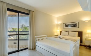 A hotel room with a bed, a nightstand, a lamp, a framed picture on the wall, and a view through a window.