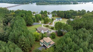 Vue aérienne d’un quartier résidentiel avec une grande maison, une maison plus petite et une jetée qui s’avance dans un lac.