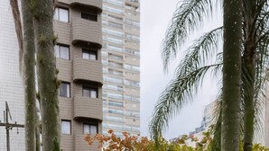 Un barbecue extérieur en briques, doté d’une poignée en métal, se dressant sur fond d’immeubles imposants et de palmiers.