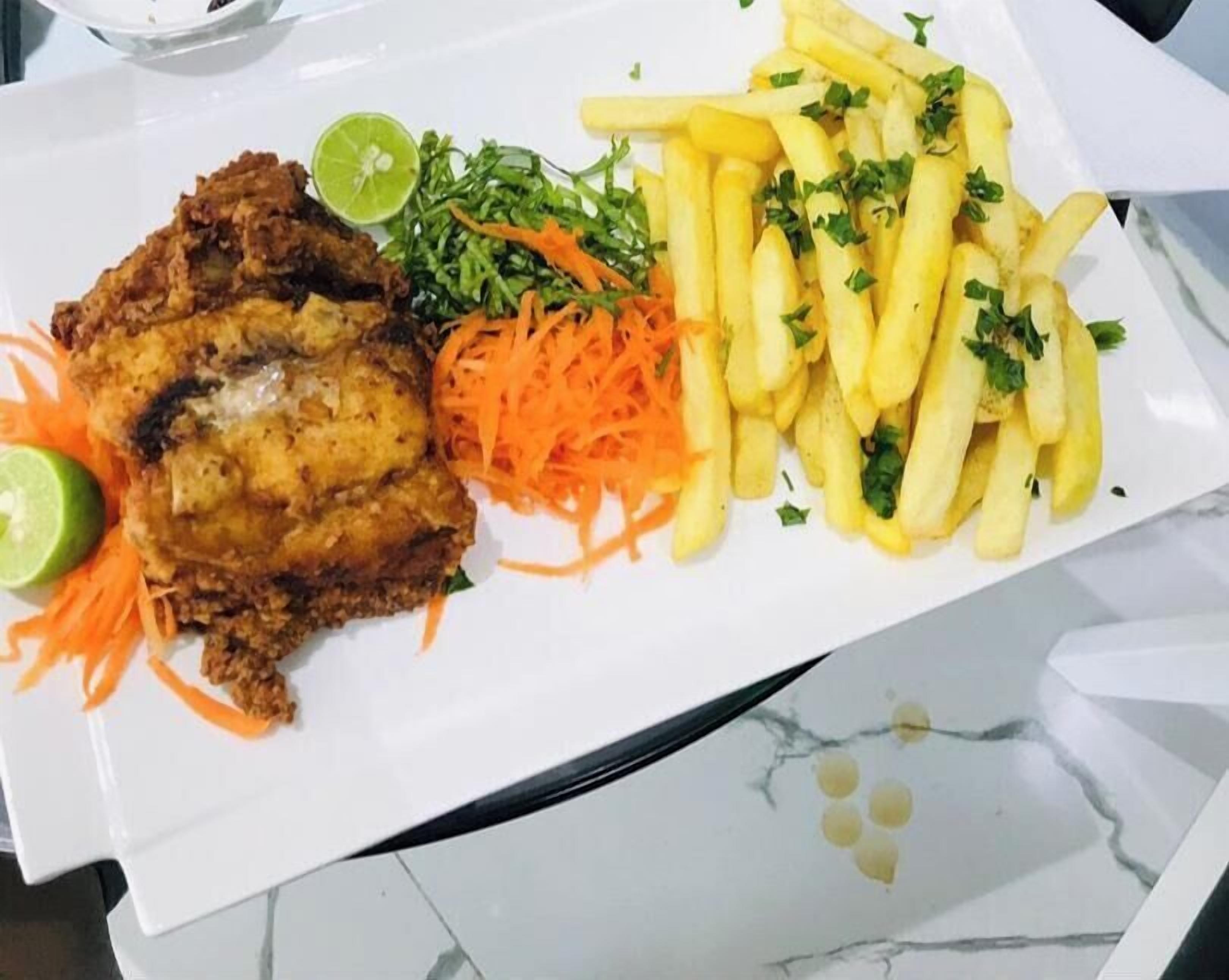 A plate with fried chicken, French fries, and a side salad.
