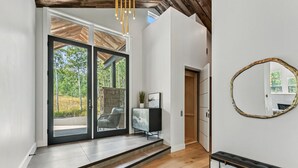 Un intérieur moderne avec un plafond en bois, une grande porte-fenêtre coulissante donnant sur un espace extérieur, un banc et un miroir mural.