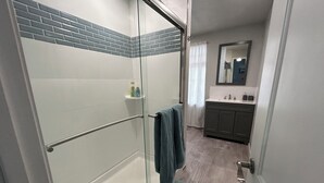 A modern bathroom with a glass shower enclosure, a towel rack, and a sink with a mirror.