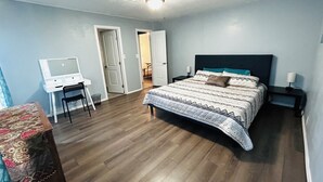 A bedroom with a bed, a desk, and a chair.