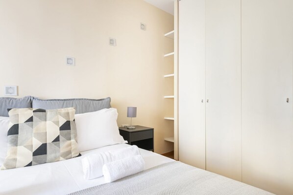 Une chambre à coucher bien rangée, avec un lit, des oreillers, une table de chevet et une armoire.