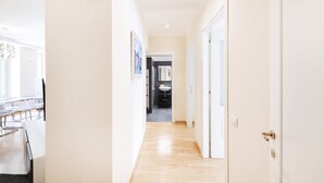 A hallway with a wooden floor, white walls, and a door on the right.