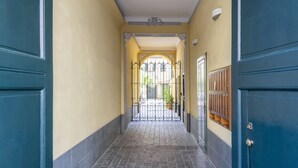 A hallway with a tiled floor, a metal gate, and a door with a window.