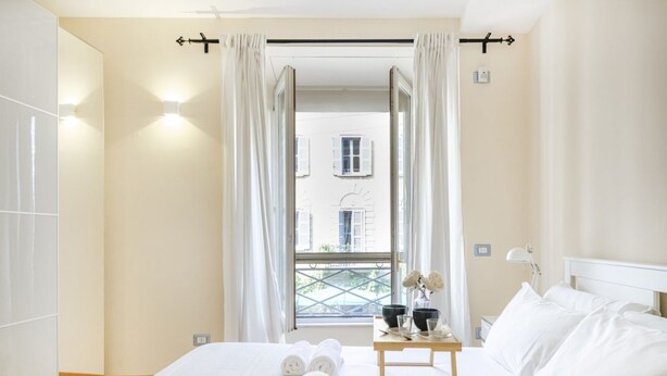 A hotel room with a bed, a table with toiletries, and a window with curtains.