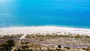 An aerial view of a beach with a road running parallel to the shore, surrounded by sparse vegetation. - Marine Holiday Home - Geographe (Geographe)