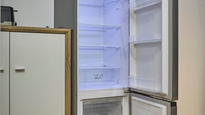 Une cuisine d’angle avec un réfrigérateur encastré, des armoires en bois et un plan de travail.