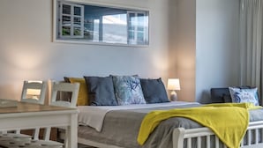 Une chambre à coucher avec un lit, des tables de chevet, une fenêtre donnant sur un paysage agréable et un rideau.