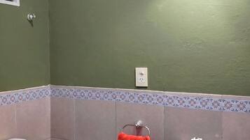 A bathroom with a green wall, a white sink, and a toilet.
