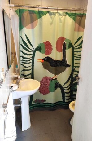 A bathroom with a shower curtain featuring a bird and leaves design, a white sink, and a toilet.