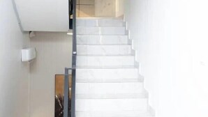 A staircase with white steps leading to a landing. - Damido's Apartment (Abuja)