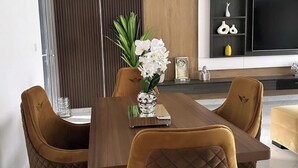 A modern dining area with a wooden table and cushioned chairs, a decorative vase with flowers, and a wall-mounted air conditioner. - Damido's Apartment (Abuja)