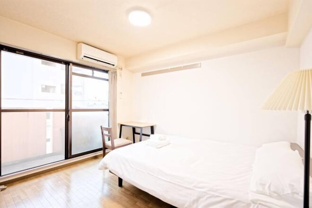 A hotel room with a bed, a chair, a small table, and a window with a view.