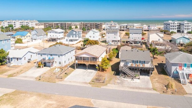 Un barrio residencial con casas, una playa al fondo y un cielo despejado.