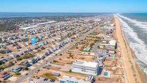 Vista aérea de un pueblo costero con una playa extensa, zonas residenciales y un gran complejo industrial.