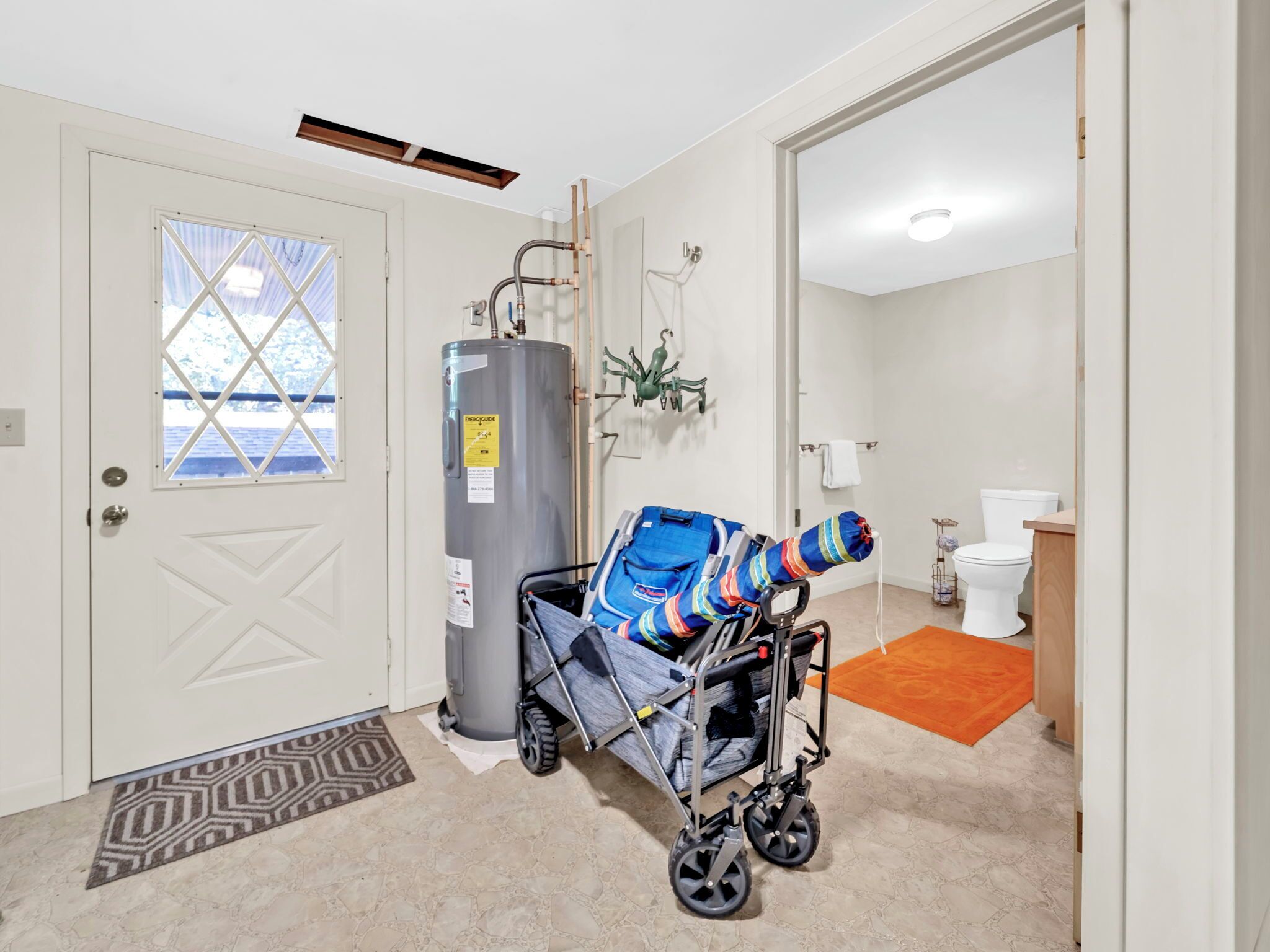 A modern bathroom with a toilet, sink, and shower. A baby stroller is parked near the door.
