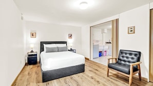 A bedroom with a bed, bedside tables, a chair, a wardrobe, and a mirror.