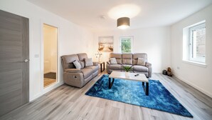 Een moderne woonkamer met twee banken, een salontafel en een blauw vloerkleed.