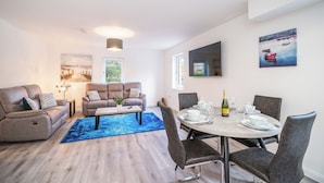 Een moderne woonkamer met een eethoek, met een zithoek, een salontafel en een eettafel gedekt voor zes personen.