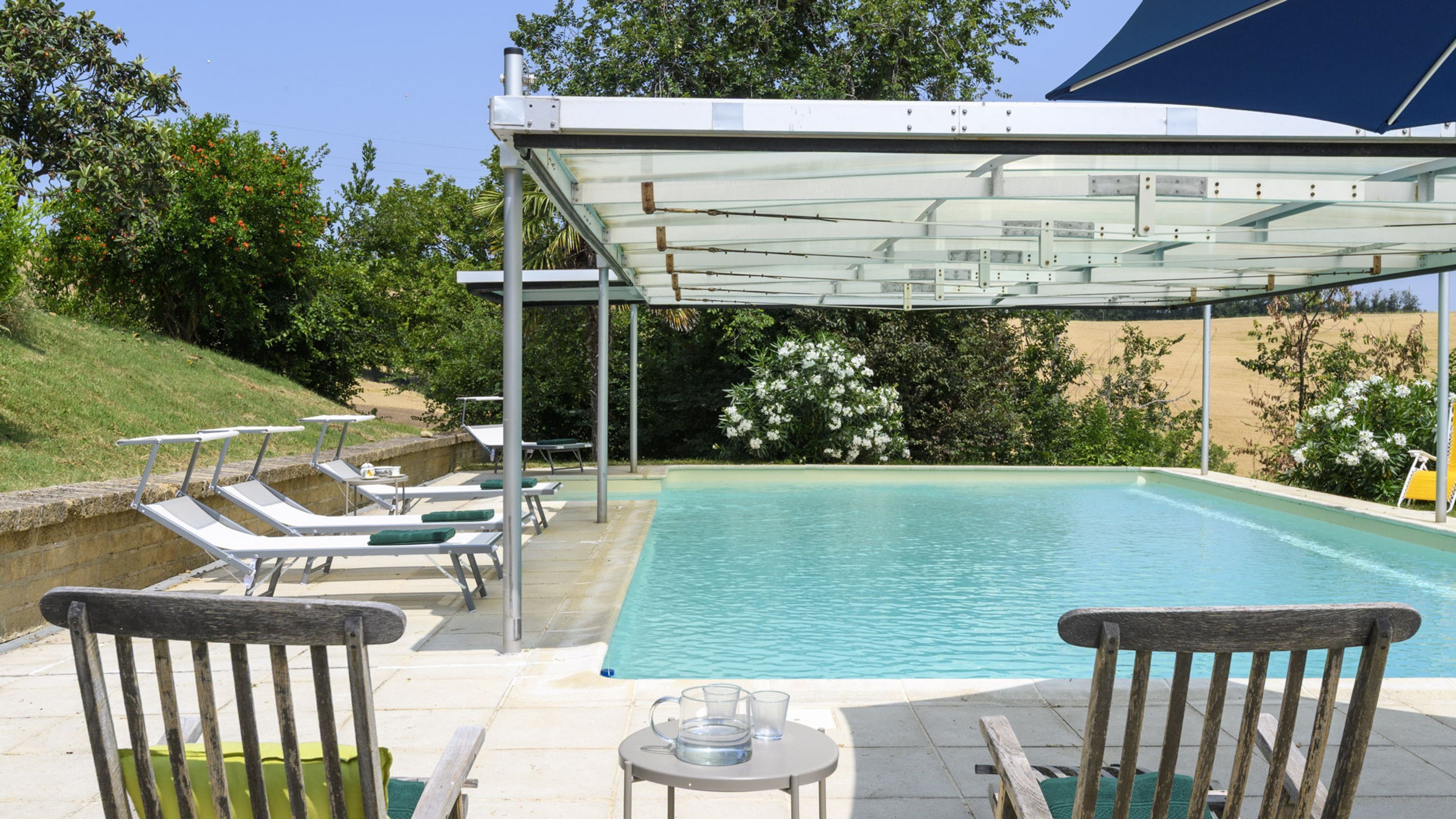 A swimming pool with lounge chairs and a covered area.