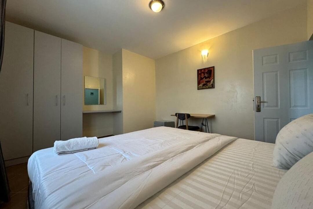 Ett hotellrum med en stor säng, ett skrivbord och en garderob.