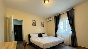 A bedroom with a bed, a desk, a chair, and a window with curtains. - The Pines Court Apartment (Gwagwalada)