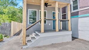 Un immeuble résidentiel doté d’un porche, d’un escalier en bois et d’un ventilateur de plafond.