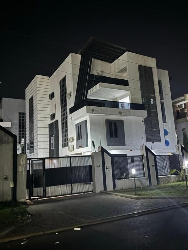 Un bâtiment moderne à plusieurs étages, doté d’une porte d’entrée imposante et d’une allée bien éclairée.