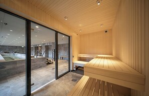 Un spa moderno con paneles de madera, una pared de vidrio y una zona de sauna.