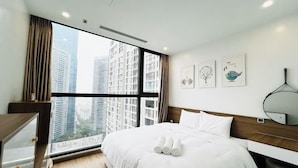 A hotel room with a large bed, a desk, and a view of tall buildings.
