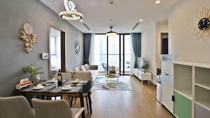 A modern living room with a dining area, large windows, and a view of the city.