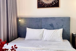 A bed with a headboard, a bedside lamp, and a wall-mounted artwork.