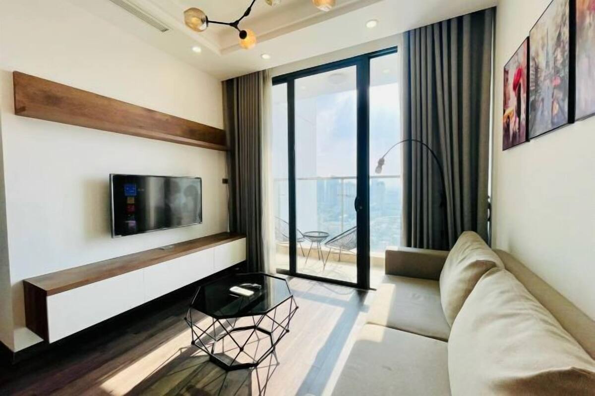 Un salon moderne doté d’un téléviseur à écran plat, d’une table basse en verre, d’un canapé et d’un balcon offrant une vue agréable.