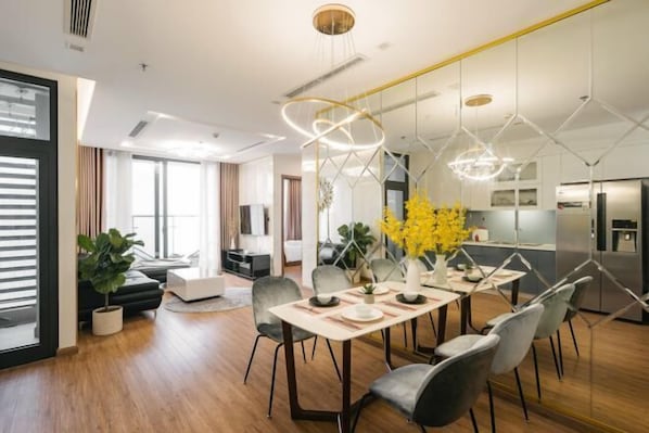 A modern dining area with a wooden table, grey chairs, and a vase of yellow flowers.