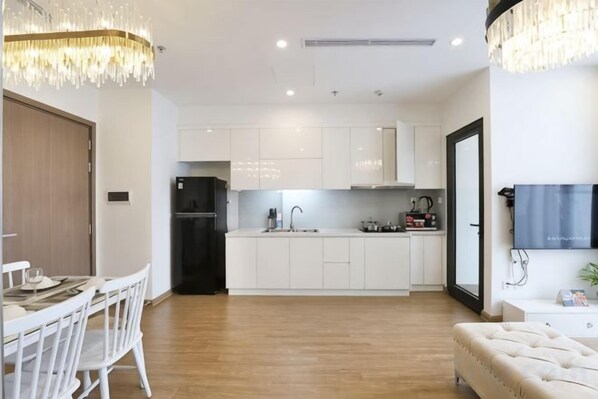 A modern kitchen with white cabinets, a black refrigerator, and a dining area with a white table and chairs.