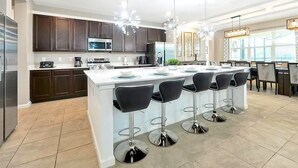 A modern kitchen with dark wood cabinets, stainless steel appliances, and a central island with bar stools.