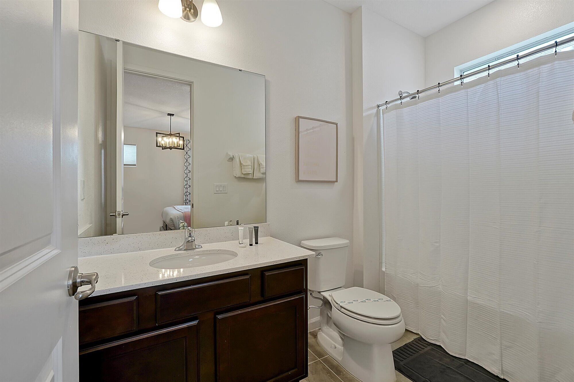 A bathroom with a double sink vanity, a toilet, and a shower curtain.
