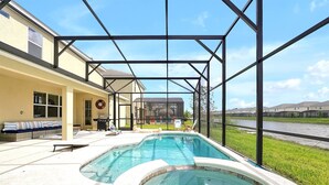 A pool area with a hot tub, outdoor seating, and a covered patio.