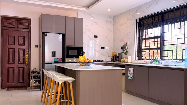 Cozinha moderna com ilha central, banquetas, micro-ondas e uma janela ampla.