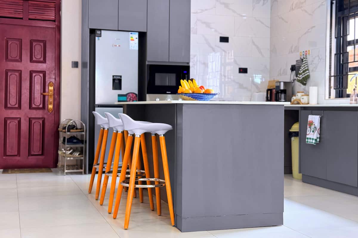A modern kitchen with grey cabinets, a marble backsplash, and a central island with stools.
