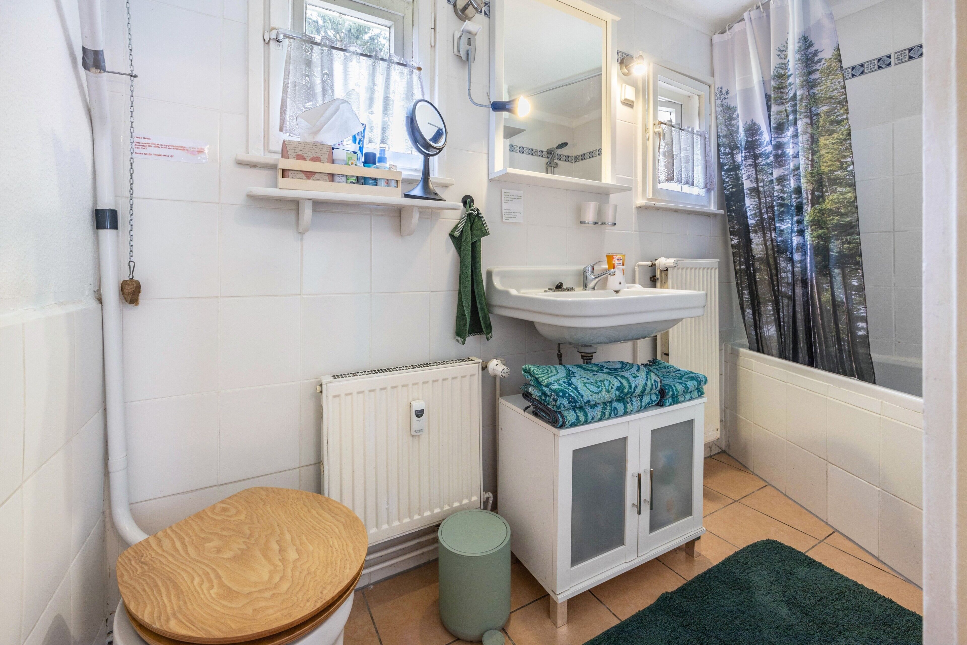A bathroom with a toilet, sink, mirror, and shower.
