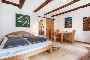 A bedroom with a wooden bed, a dining table with chairs, and artwork on the walls.