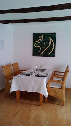 Ein Essbereich mit einem Tisch, gedeckt für vier Personen, umgeben von Korbstühlen mit Kissen.